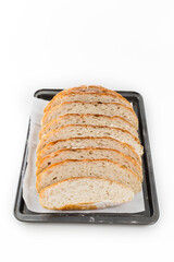 Freshly homemade bread sliced on a baking paper in a baking tray, light and airy inside with a crunchy rustic crust.
