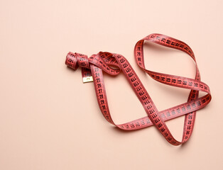 twisted white measuring tape on a beige background