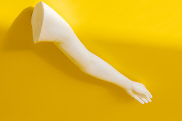 arm of a white dummy model at yellow background. Yellow minimal abstract background