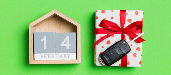 Top view of car key on a gift box with red hearts and festive calendar on colorful background. The fourteenth of february. Present for Valentine's Day concept