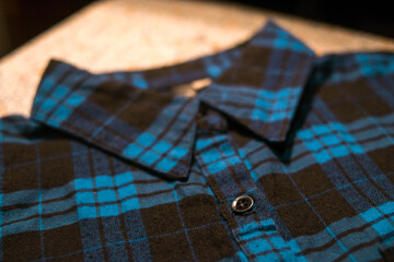 Collar of a dark blue plaid shirt with black buttons