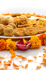 diwali snacks kept on Rangoli design made with flower petals of rose and marigold  for Diwali celebration in India