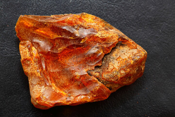 Natural bright piece of amber on a black background. Sun stone. Semiprecious mineral. Material for jewelry. Ancient petrified resin. Inclusions in amber. Skin texture. Copal. Fossil