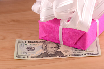 Dollars money along with a gift, a symbol of the crisis, venality, hoarding and wealth. American money on wooden background.