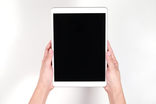 Top view image of woman hands holding a blank screen tablet computer against a white background.