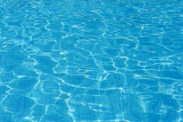 Fototapeta na wymiar Sunny rippling blue surface of outdoors swimming pool. Abstract photo background.