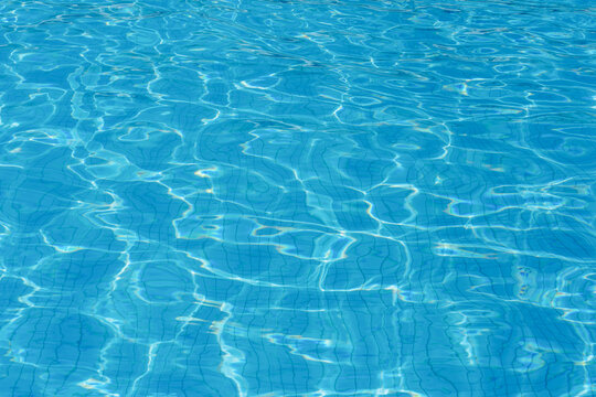 Sunny rippling blue surface of outdoors swimming pool. Abstract photo background.