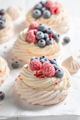 Delicious mini Pavlova cake with whipped cream and frozen fruit