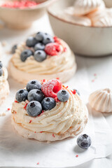 Sweet mini Pavlova cake with whipped cream and frozen fruit