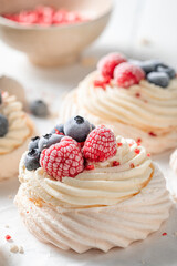 Creamy mini Pavlova cake with frozen fruits and meringue