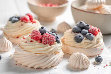 Crunchy mini Pavlova cake with whipped cream and frozen fruit