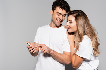  casual young couple in white t-shirts with smartphone isolated on grey