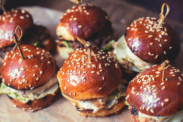 Burger mini burgers snacks on a wooden table with craft paper, beautifully decorated catering banquet table on corporate christmas birthday party event or wedding celebration