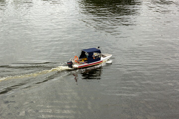General plan of the outboard motorboat sails on the river, the cabin of the boat is covered with...