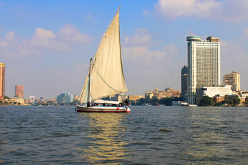 A boat with a sail sails on the Nile River overlooking the panoramas of Cairo