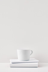 The mug stands on a stack of books on a white background. Natural and eco-friendly materials. Copy space, mock up