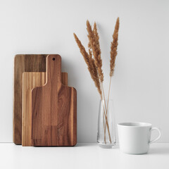 A mug, a transparent vase, and a wooden cutting board. Eco-friendly materials in the decor of the room, minimalism. Copy space, mock up.