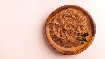 Cocoa powder in a wooden bowl on a pink background. Cocoa product. Copy space.