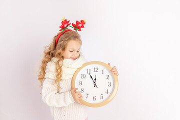 baby girl holding a clock over white isolated background with the sweater, place for text, concept...