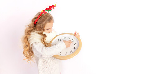 baby girl holding a clock over white isolated background with the sweater, place for text, concept...