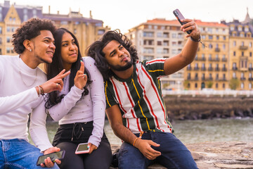 Lifestyle, three black friends having fun and taking a selfie. Afro hair boy, brunette boy with long hair and brunette girl