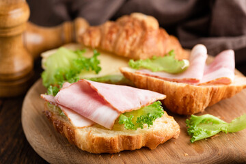 Croissant with ham, cheese and lettuce salad. Croissant open sandwich