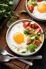Fried egg with tomato avocado salad. Healthy breakfast meal. Top view