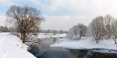 Obraz na płótnie Canvas Photo the snow-covered river did not freeze in winter.The river flows in winter. Snow on the branches of trees. Reflection of snow in the river. Huge snowdrifts lie on the Bank of the stream.