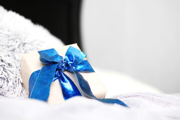 Gift with a blue bow. Gift in craft paper. Beautiful blue bow. A Christmas gift. New Year. Gift close up