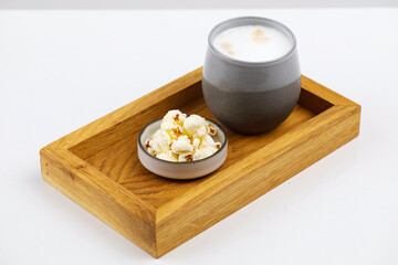 Drewniana taca z glinianym naczyniem z napełnionym żurkiem obok w miseczce kostki sera z warzywami, całośc na białym tle © JDziedzic