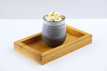 Drewniana taca z glinianym naczyniem z napełnionym żurkiem obok w miseczce kostki sera z warzywami, całośc na białym tle © JDziedzic