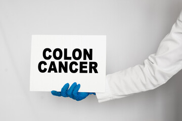 The doctor's blue - gloved hands show the word COLON CANCER - . a gloved hand on a white background. Medical concept. the medicine