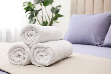 Fototapeta na wymiar Rolled soft clean towels on bed indoors