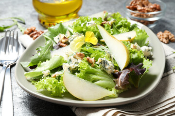 Fresh salad with pear served on grey table