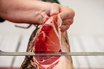 Manos con cuchillo cortando una loncha de jamón