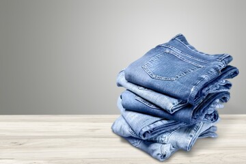 Pile of trendy blue jeans over wooden desk