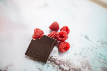 Bitten chocolate bar and raspberries on a colorful placemat
