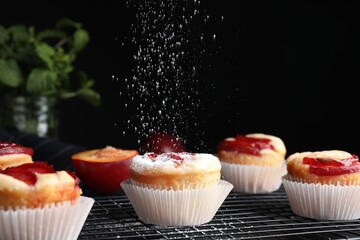 Sprinkling plum cupcakes with powdered sugar at table