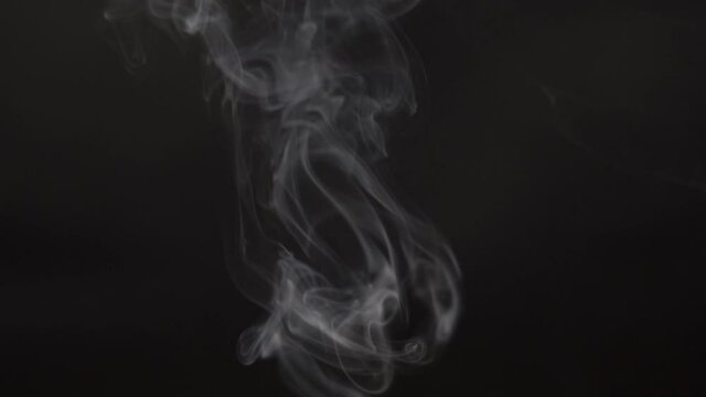 Slow motion shot of white smoke in front of the black background. Realistic Atmospheric Gray Smoke on Black Background. White Fume Slowly Floating Rises Up. Abstract Smoke isolated on black background