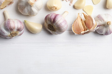 Obraz na płótnie Canvas Fresh organic garlic on white wooden table, flat lay. Space for text