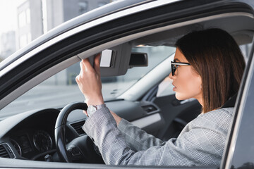 Fototapeta na wymiar businesswoman adjusting rearview mirror while sitting in car, stock image