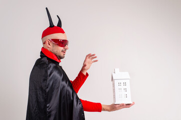 Adult caucasian man in halloween costume with decorative building in his hands isolated on white.