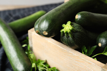Raw green zucchinis in wooden crate, closeup