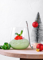 Avocado mousse with sour cream and red caviar in the glass on the wooden table and Christmas decorations around. Festive appetizer