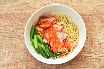 Chinese yellow egg noodles topping slice barbecue pork and boiled cabbage dressing sweet red gravy sauce on bowl