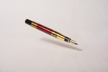 Antique fountain pen, fountain pen released in the air with drop shadow on light gray background,...