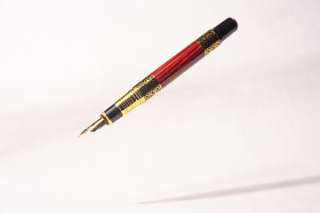 Naklejka premium Antique fountain pen, fountain pen released in the air with drop shadow on light gray background, selective focus.