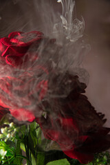 Cascade of smoke beautifully covering a bouquet of fabric flowers, abstract background, selective focus.