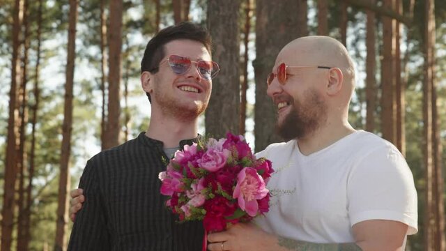 Portrait of queer couple happy together. Gay wedding concept. Two men with flower bouquet and ring on finger smile and hug. Relationship Goals. LGBTQI, Pride Event, LGBT Pride Month, Gay Pride Symbol