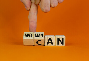 Woman can symbol. Male hand flips cubes and changes the word 'woman' to 'can'. Beautiful orange background. Copy space. Feminist and motivational concept.